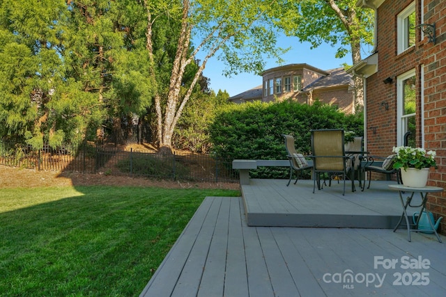 deck with outdoor dining area, fence, and a yard