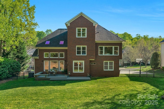 back of house with a shingled roof, a fenced backyard, brick siding, and a yard