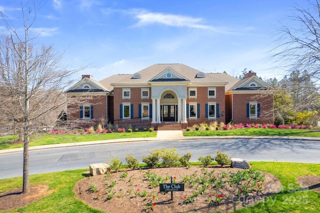 view of front of property with french doors, brick siding, and a front yard