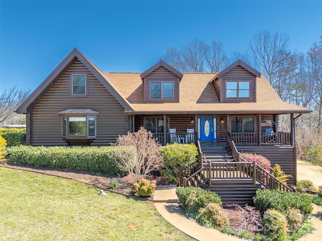 view of front of home featuring log siding, covered porch, a shingled roof, and a front lawn