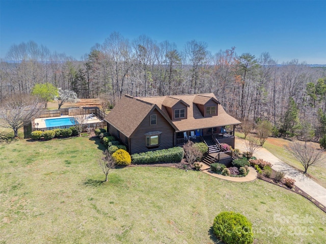 view of front of house featuring an outdoor pool, stairway, a wooded view, driveway, and a front yard