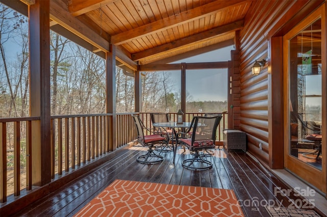 sunroom with outdoor dining area and beam ceiling