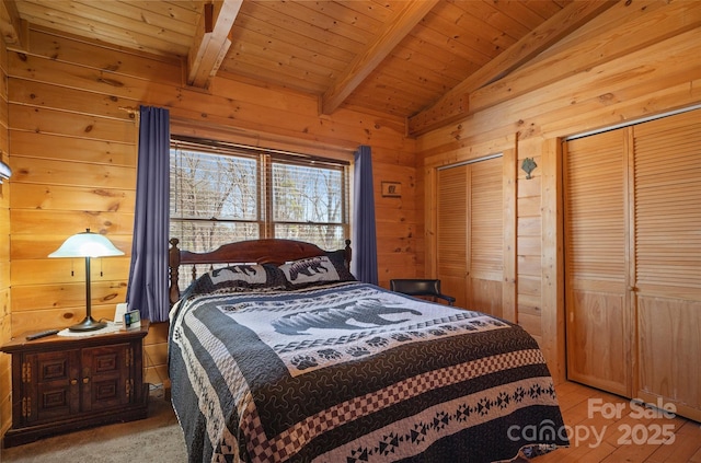 bedroom with wooden ceiling, vaulted ceiling with beams, wooden walls, and multiple closets