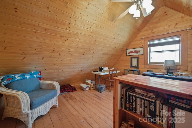 interior space with hardwood / wood-style floors, lofted ceiling, a ceiling fan, and wooden walls