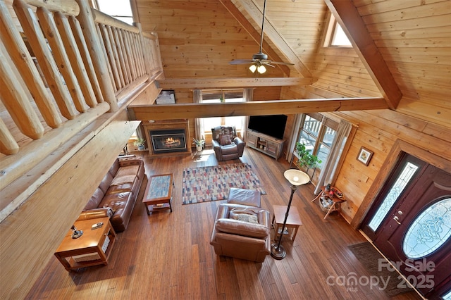 living area featuring high vaulted ceiling, wood walls, beamed ceiling, and hardwood / wood-style flooring