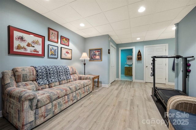 living room with baseboards, wood finished floors, recessed lighting, and a paneled ceiling