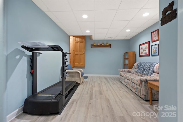 exercise room with baseboards, wood finished floors, a paneled ceiling, and recessed lighting