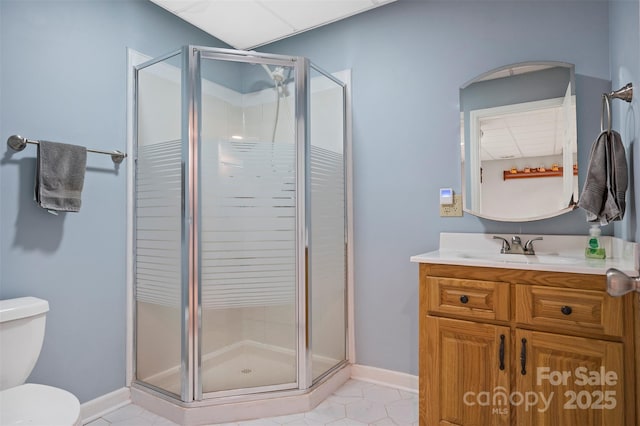 full bath featuring a stall shower, tile patterned floors, toilet, vanity, and baseboards