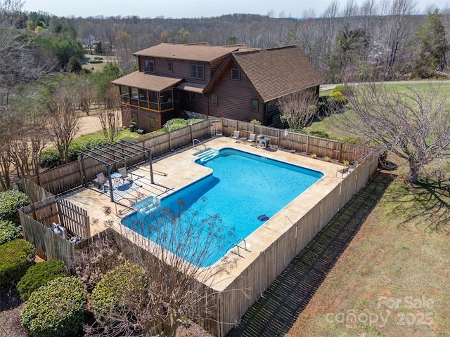 community pool with a patio, fence, and a view of trees