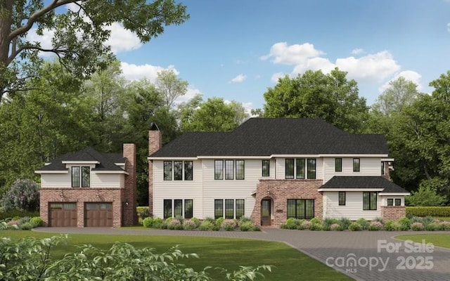view of front of property featuring driveway, a front yard, a garage, brick siding, and a chimney