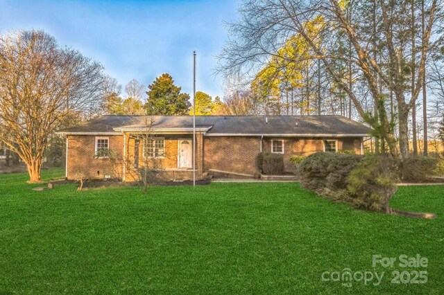 back of property with a yard, brick siding, and crawl space