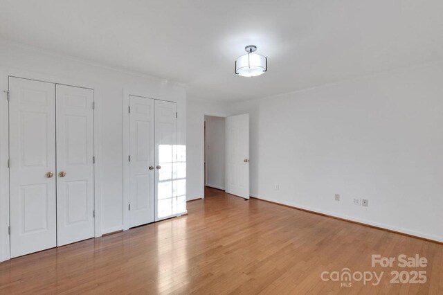 2750 Morgan Rd, Gold Hill, NC 28071 - unfurnished bedroom with two closets, baseboards, and wood finished floors