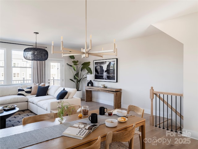 dining space with baseboards, a notable chandelier, and wood finished floors