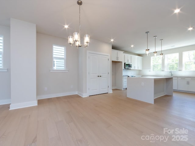 kitchen with a notable chandelier, a center island, white cabinetry, and light countertops