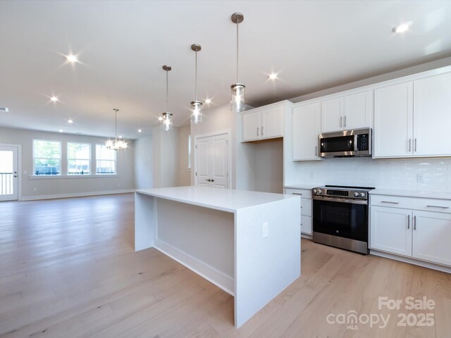 kitchen with a chandelier, light wood-type flooring, stainless steel appliances, and recessed lighting