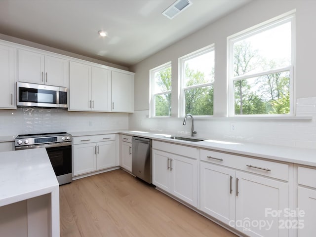 kitchen featuring backsplash, appliances with stainless steel finishes, a sink, and visible vents