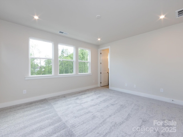 carpeted empty room with baseboards, visible vents, and recessed lighting