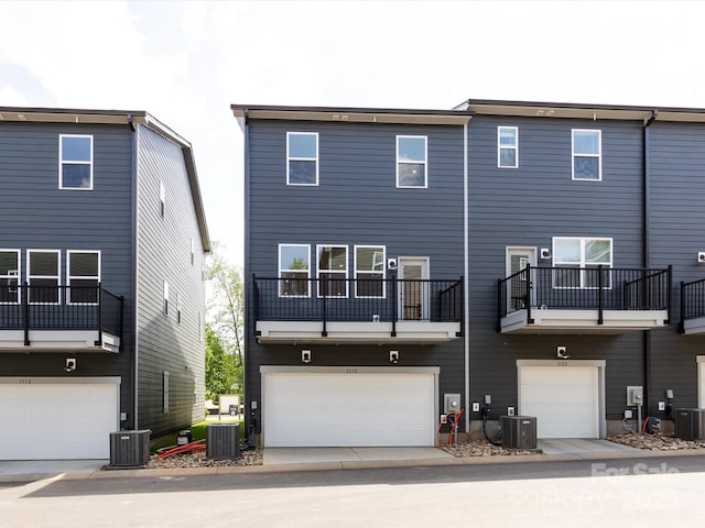 rear view of property with central air condition unit and an attached garage