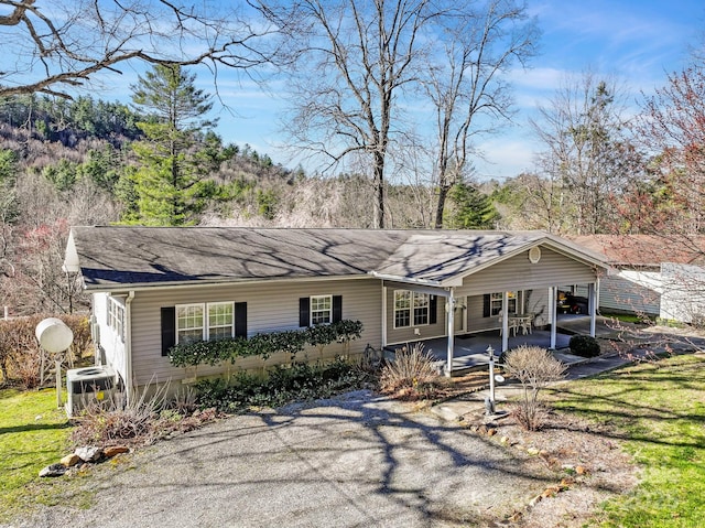 view of front of home with central AC unit, a carport, and a front lawn