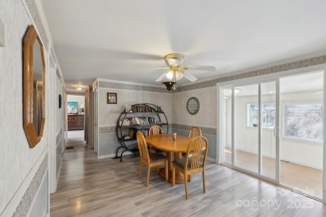 dining room featuring light wood-type flooring, baseboards, wallpapered walls, visible vents, and a ceiling fan