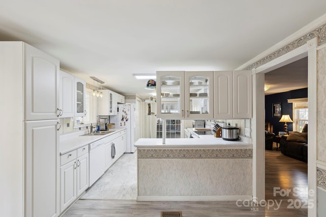kitchen featuring plenty of natural light, white appliances, glass insert cabinets, and a sink