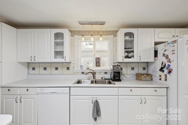 kitchen featuring white cabinets, a sink, glass insert cabinets, and white appliances