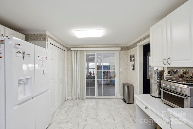 kitchen featuring light countertops, ornamental molding, white refrigerator with ice dispenser, marble finish floor, and white cabinets