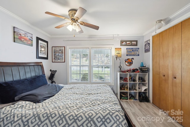 bedroom with a closet, ornamental molding, light wood-style floors, and ceiling fan