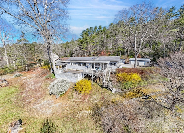 back of property with a wooded view, a wooden deck, and stairway