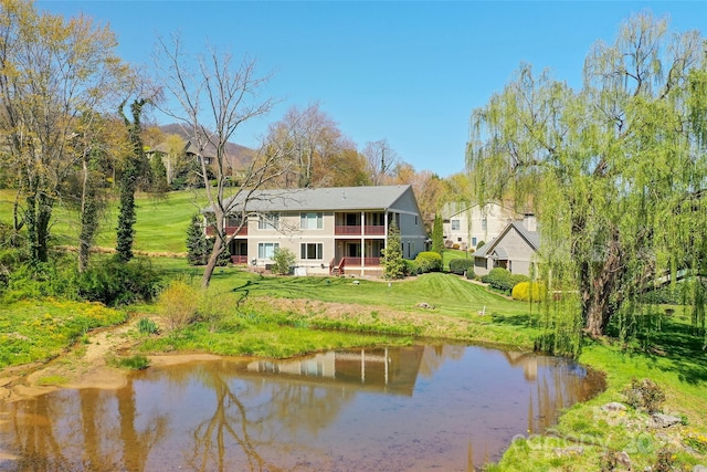 back of house featuring a water view, a yard, and a balcony