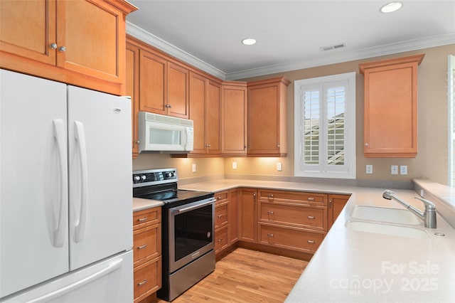 kitchen featuring crown molding, a sink, white appliances, light countertops, and visible vents