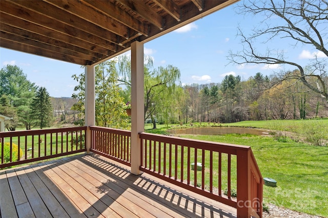 wooden terrace with a lawn and a view of trees
