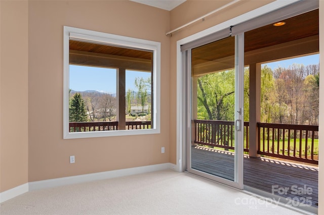 doorway with baseboards and carpet flooring