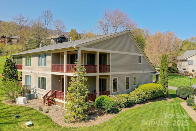 rear view of house featuring a lawn, cooling unit, and a balcony