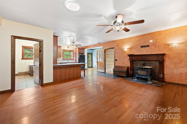 731 Old Fort Rd, Fairview, NC 28730 - unfurnished living room with a wood stove, a ceiling fan, light wood-style floors, and baseboards