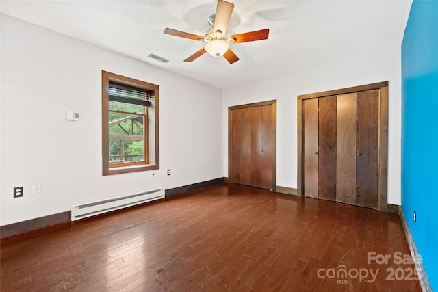 731 Old Fort Rd, Fairview, NC 28730 - unfurnished bedroom featuring baseboard heating, wood finished floors, two closets, and a ceiling fan