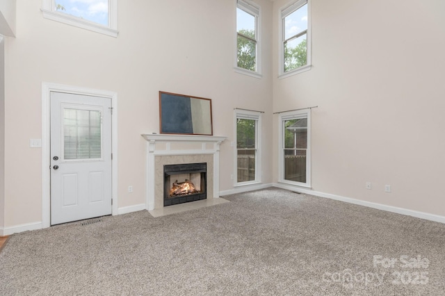 unfurnished living room featuring carpet floors, a high ceiling, and plenty of natural light