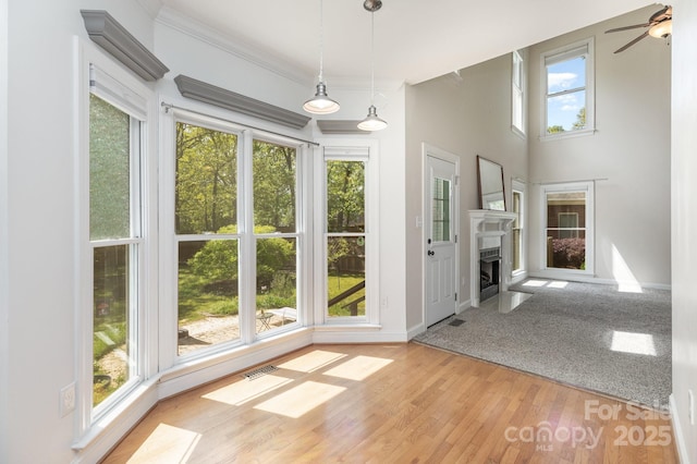 unfurnished dining area with ceiling fan, baseboards, wood finished floors, visible vents, and ornamental molding
