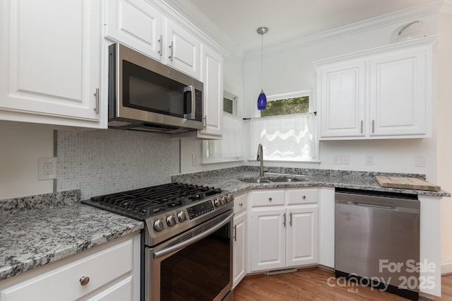 kitchen featuring white cabinetry, appliances with stainless steel finishes, a sink, and light wood-style floors