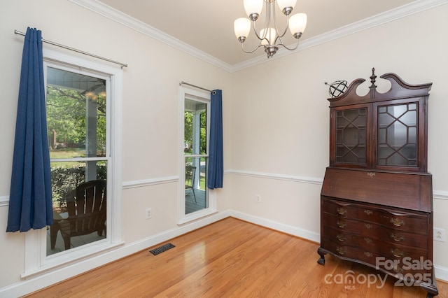 spare room with visible vents, crown molding, wood finished floors, baseboards, and a chandelier