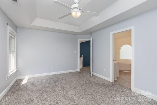unfurnished bedroom with visible vents, baseboards, carpet floors, and a tray ceiling