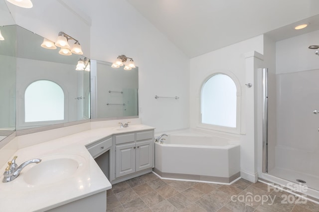 bathroom featuring a sink, a garden tub, double vanity, and lofted ceiling