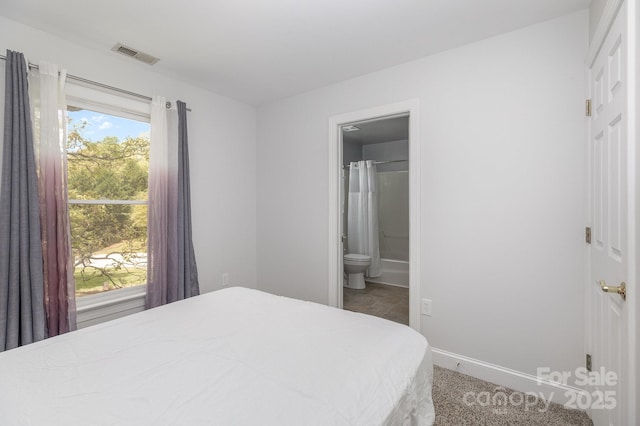 bedroom with baseboards, visible vents, and ensuite bathroom