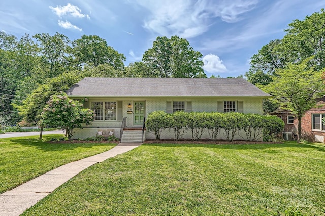 single story home featuring roof with shingles, brick siding, a front yard, and cooling unit