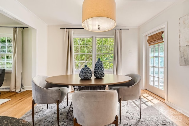 dining space with baseboards, crown molding, and light wood-type flooring