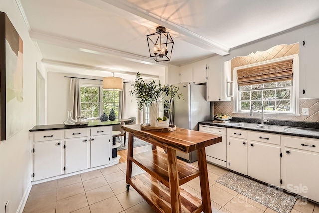 kitchen with dark countertops, white dishwasher, a sink, and a healthy amount of sunlight