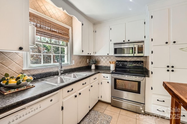 kitchen featuring dark countertops, tasteful backsplash, a sink, stainless steel appliances, and ornamental molding