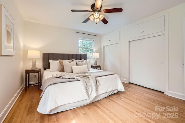 bedroom with ceiling fan, baseboards, multiple closets, and light wood-style flooring