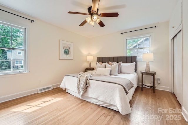 bedroom with visible vents, a closet, baseboards, light wood-style flooring, and ceiling fan