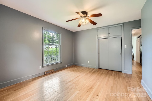 unfurnished bedroom featuring light wood-type flooring, a ceiling fan, baseboards, and a closet